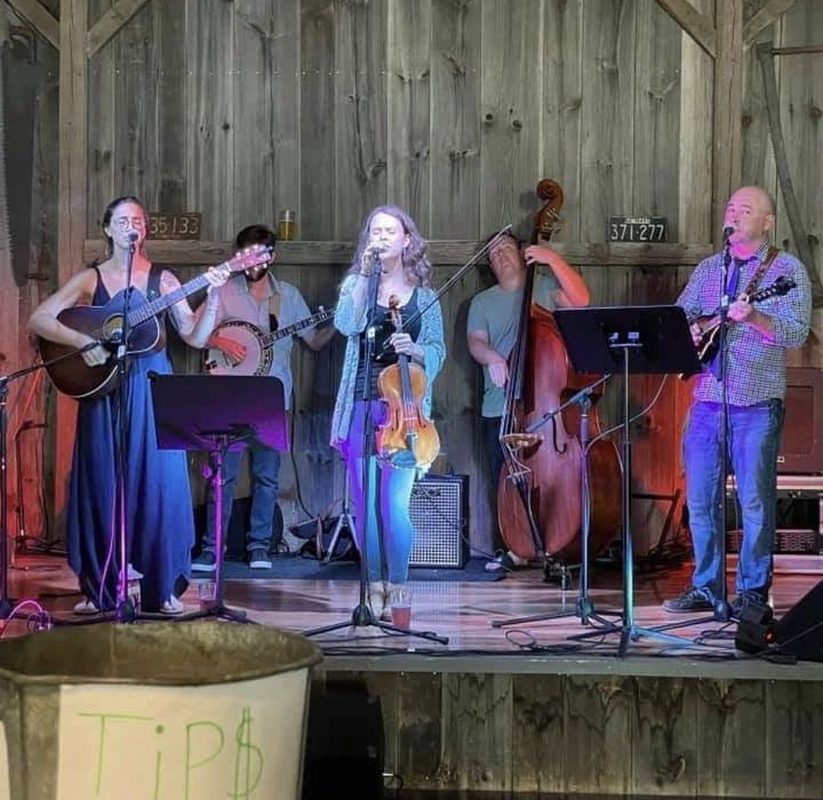 Brianna center stage with her viola, with a string band in a rustic barn