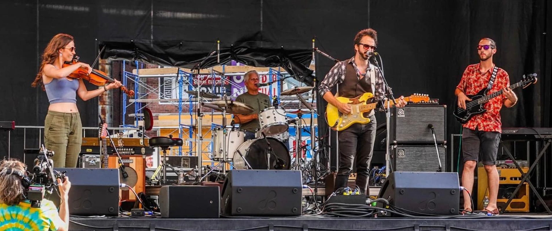 Brianna playing viola on an outdoor festival stage with a band