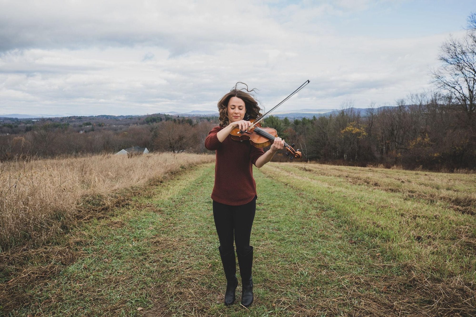 Brianna playing viola in an open autumn field, hair blowing in the wind