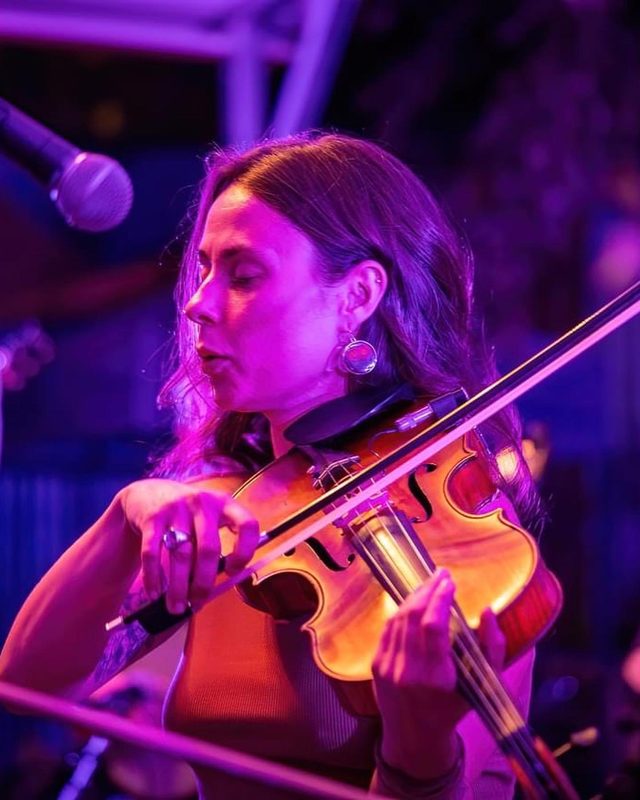 Brianna playing viola on stage under purple and pink lights